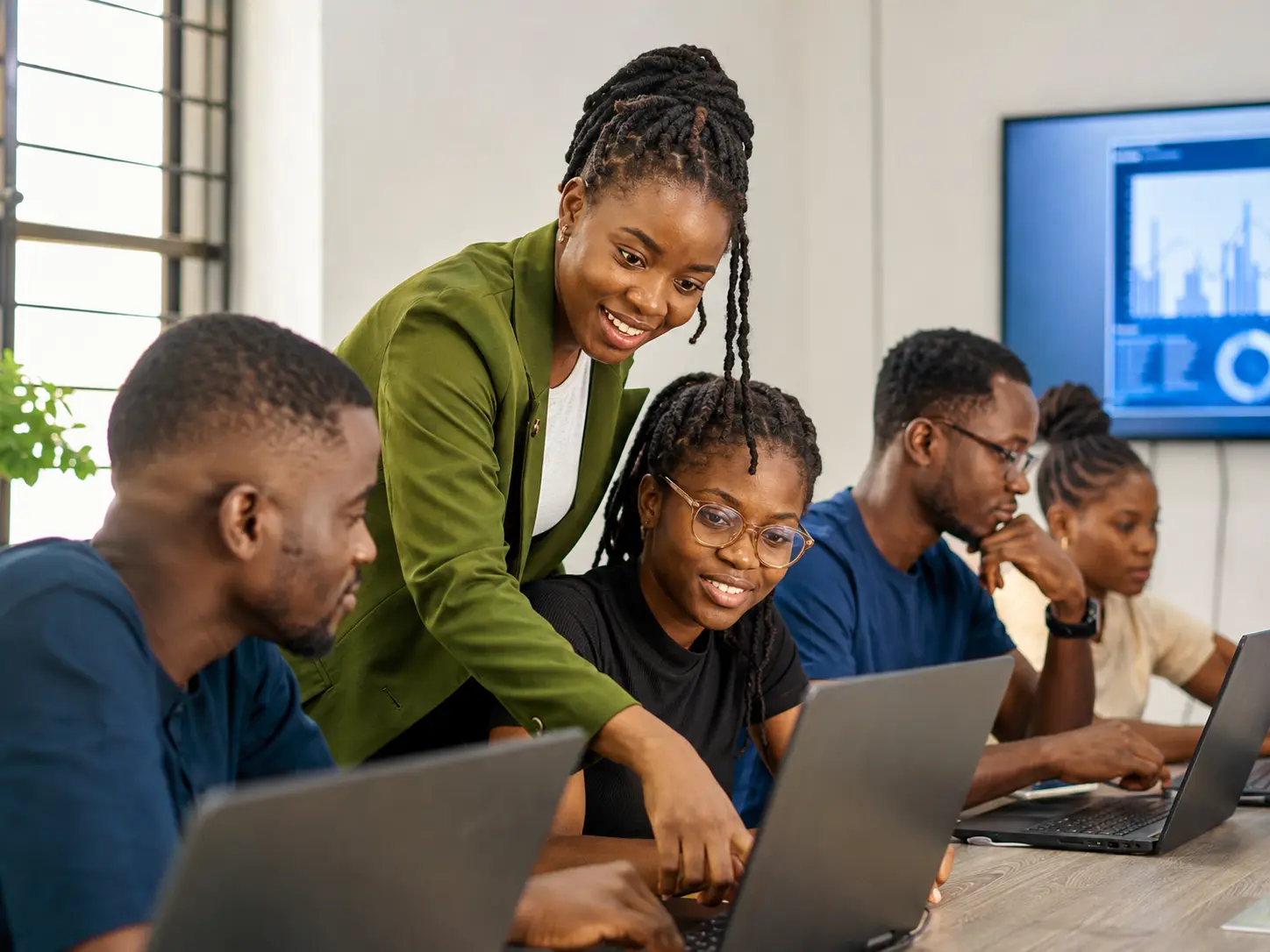 African technology instructor helping learners during a practical computer training session
