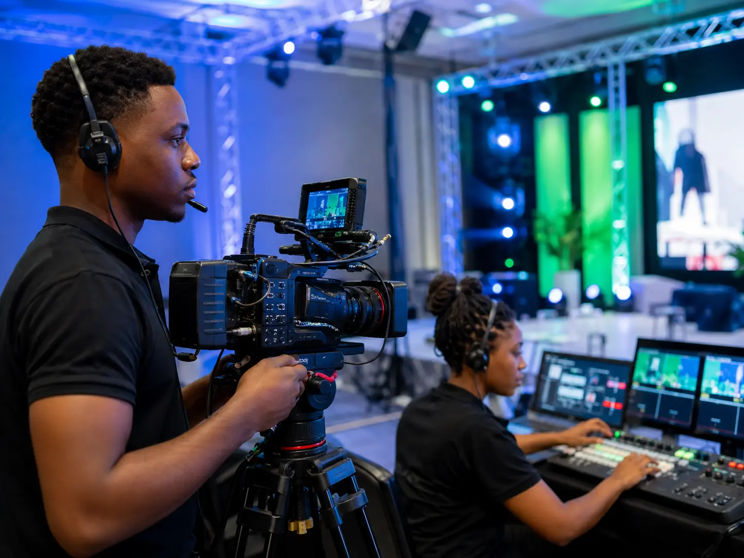 African camera operator and live production technician working at a professionally lit event